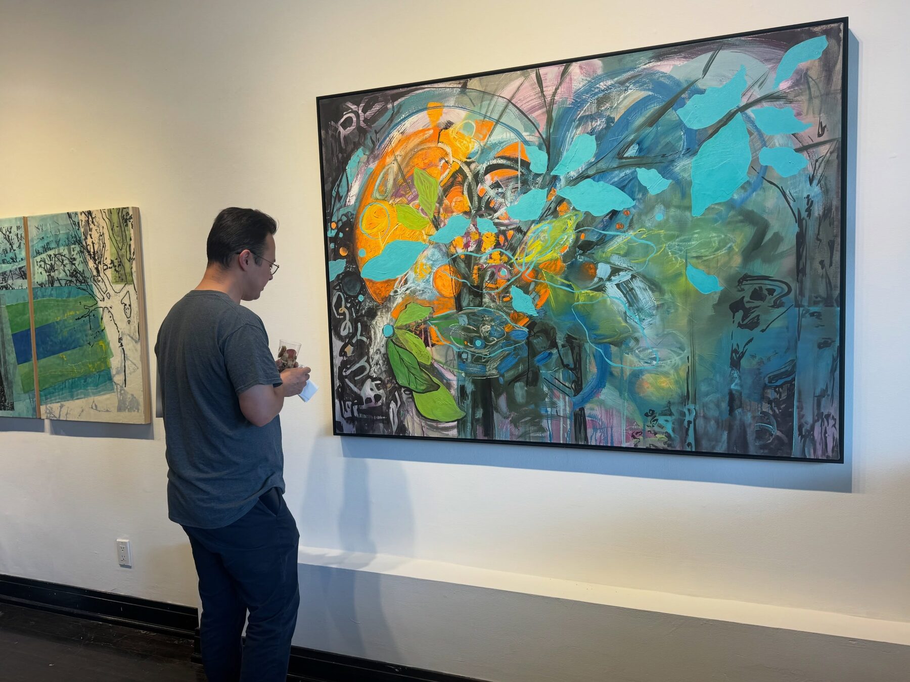 Guest viewing a large abstract painting at the Art In Transit opening