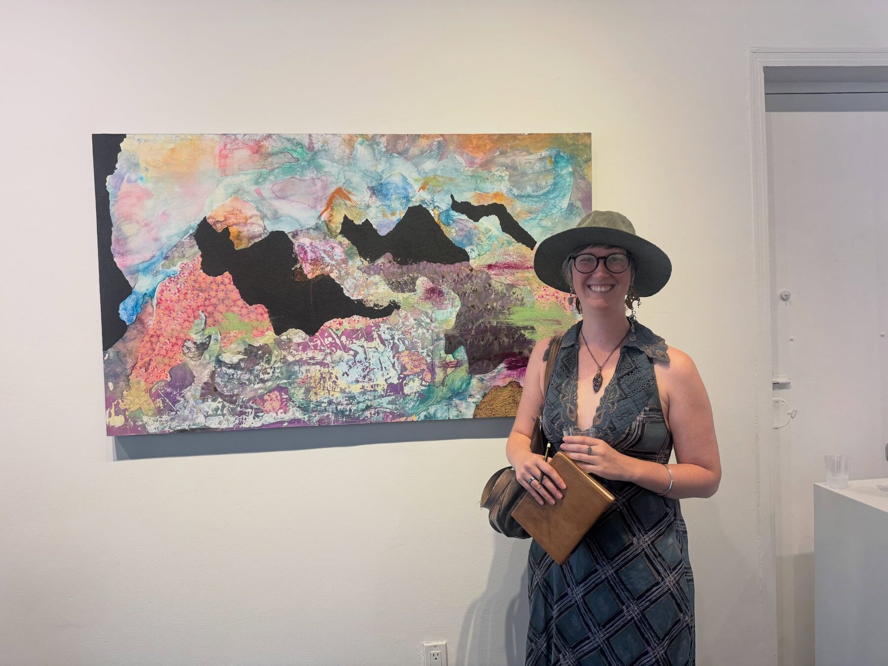 Artist beside a mixed-media landscape at the Art In Transit opening