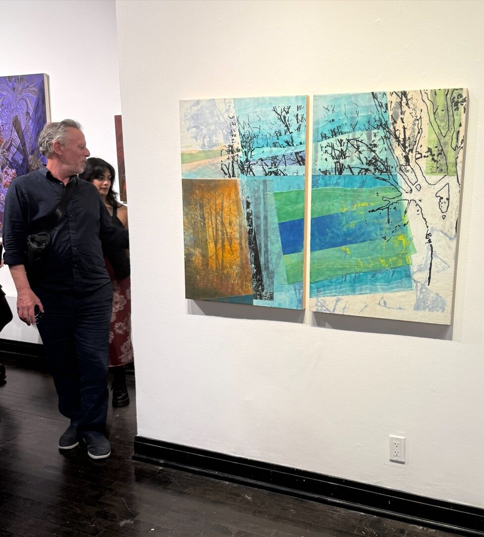 Guests viewing the encaustic tree diptych at the Art In Transit opening