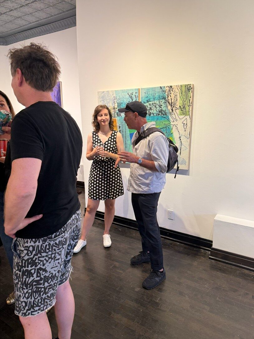 Guests in conversation beside artwork at the Art In Transit opening